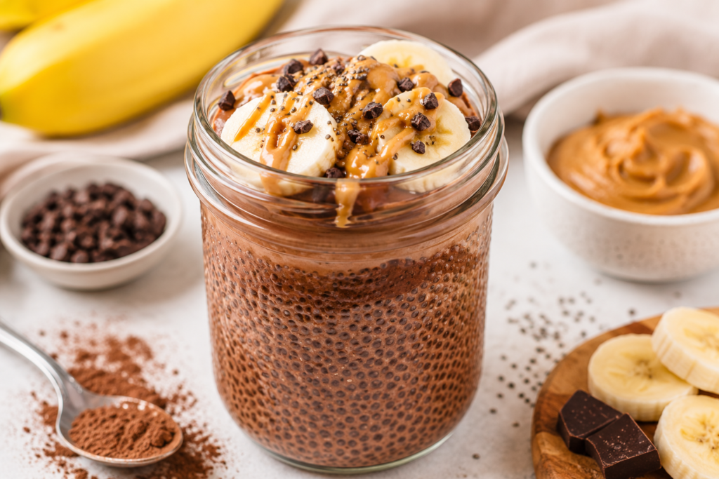 Chocolate banana peanut butter chia pudding in a glass jar topped with banana slices, peanut butter drizzle, chia seeds, and dark chocolate chunks.