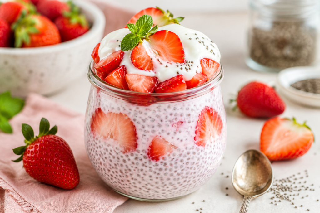Strawberry vanilla yogurt chia pudding in a glass jar topped with fresh strawberries, Greek yogurt, chia seeds, and mint.